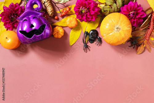 Creative halloween concept backdrop. Halloween purple jack o lantern with burning candles  pumpkins on a light brown background. View from above. Copy space.