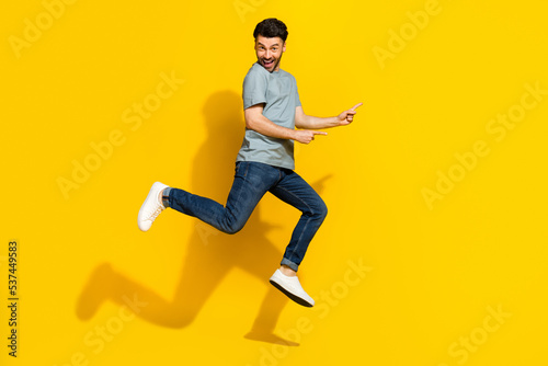 Full length photo of positive funky man dressed trendy clothes arm presenting empty space isolated on yellow color background