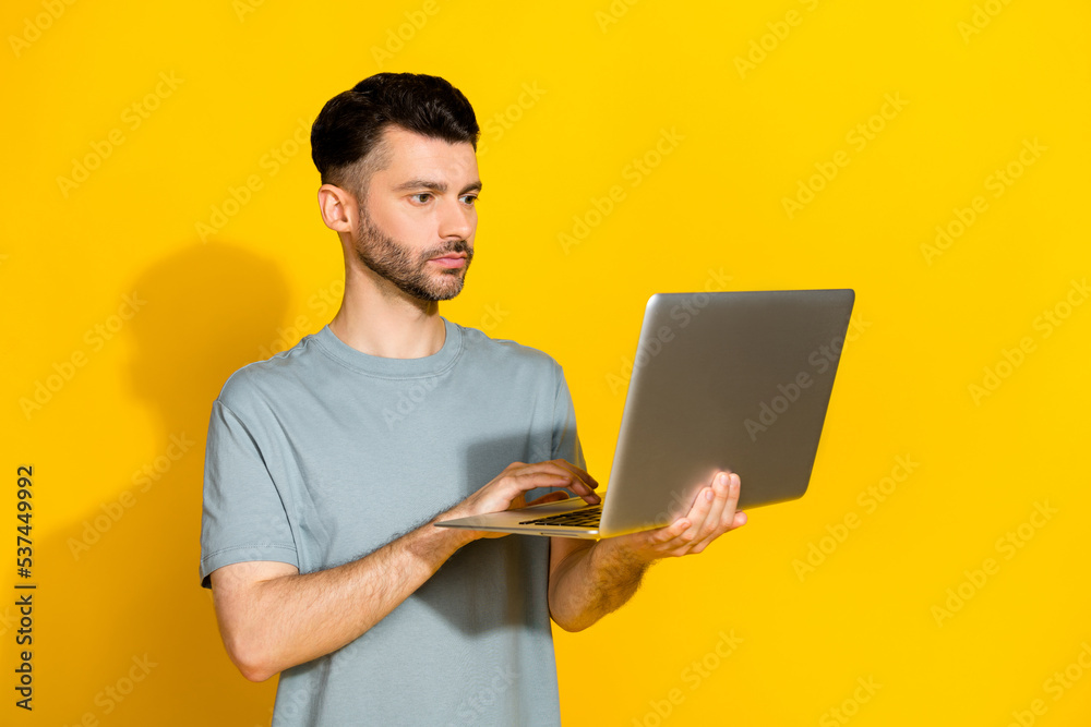 Photo of serious confident professional businessman hold new netbook typing programmer it development owner isolated on bright yellow color background Photo of serious confident professional businessman hold new netbook typing programmer it development owner isolated on bright yellow color background