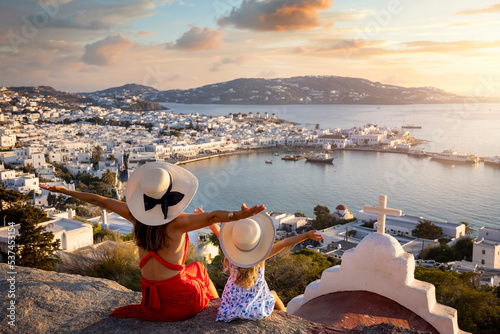 Obraz na płótnie A happy mother and daughter on family holidays overlook the town of Mykonos island during a summer sunset, Cyclades, Greece w salonie