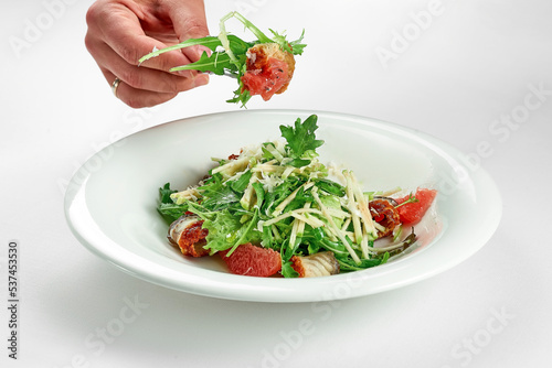 Wallpaper Mural Hand takes an eel and grapefruit salad from a white plate on a white tablecloth. Close-up, selective focus Torontodigital.ca