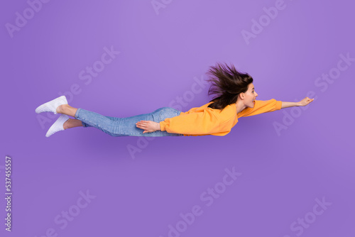 Side profile photo of young funny excited crazy girl flying vertical positive mood childish superhero enjoy carefree isolated on bright purple color background