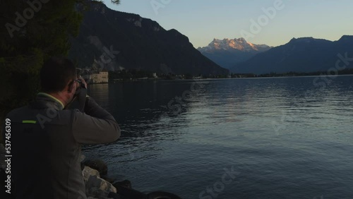 middle-aged man photographs the castle of Chillon in Switzerland and during the golden hour. photo