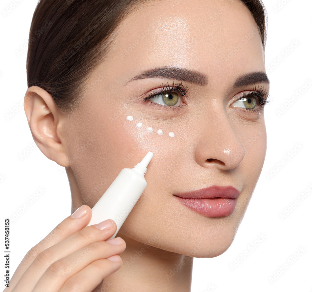 Young woman applying cream under eye on white background Young woman applying cream under eye on white background