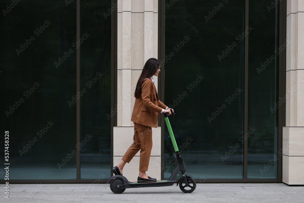 Businesswoman riding electric kick scooter on city street Businesswoman riding electric kick scooter on city street