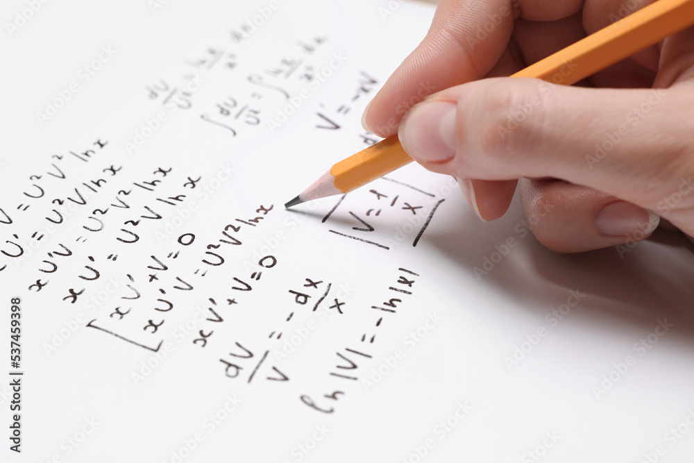 Student writing different mathematical formulas on paper, closeup Student writing different mathematical formulas on paper, closeup