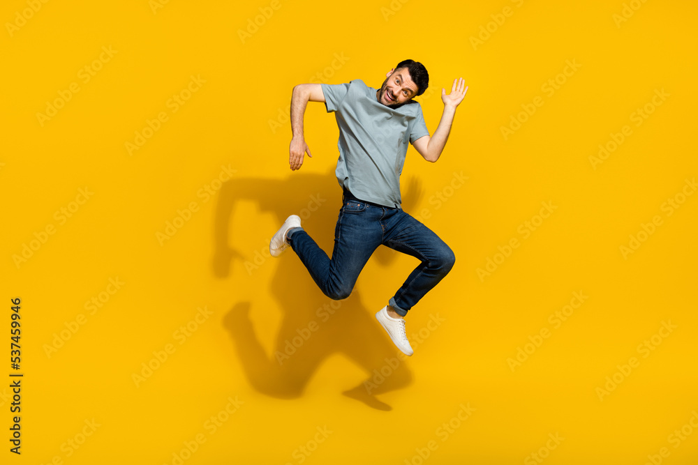 Full length portrait of satisfied glad young person jumping arms make moves isolated on yellow color background