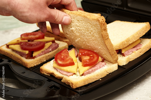 a man cooking sandwiches in a sandwich maker puts a piece of bread in a mold