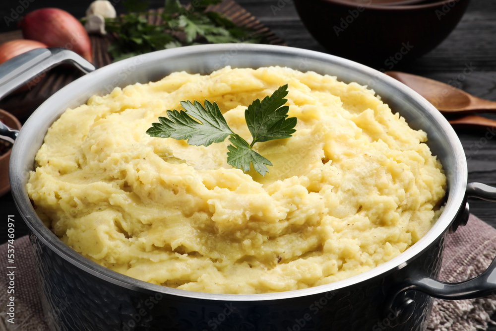 Pot of tasty mashed potatoes with parsley on black wooden table, closeup Pot of tasty mashed potatoes with parsley on black wooden table, closeup