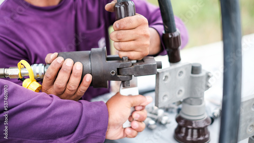 Two electrician builder workers installing high-voltage cable.Hydraulic tongs crimping that is used by workers to crimp ground wires in construction site at oil and gas plant or chemical plant.