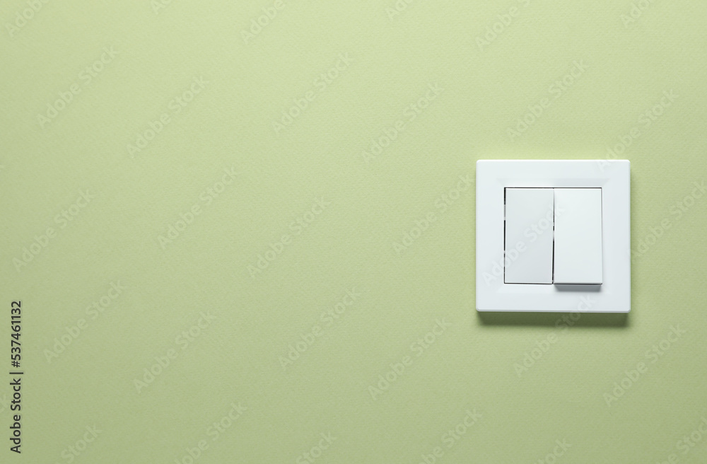 Modern plastic light switch on green background. Space for text Modern plastic light switch on green background. Space for text