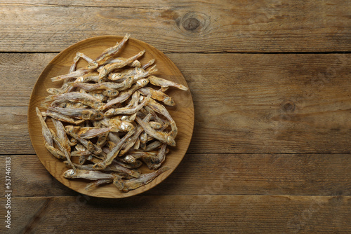 Delicious dried anchovies on wooden table, top view. Space for text