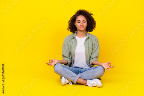 Full length photo of cute young lady curly hair sit lotus pose enjoy meditate wear trendy khaki clothes isolated on yellow color background