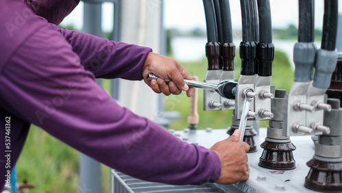 Two electrician builder workers installing high-voltage cable.Hydraulic tongs crimping that is used by workers to crimp ground wires in construction site at oil and gas plant or chemical plant.