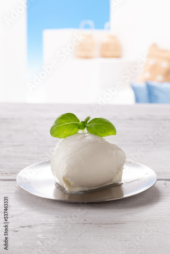 mozzarella with basil leaf on round silver plate, resting on white wooden table