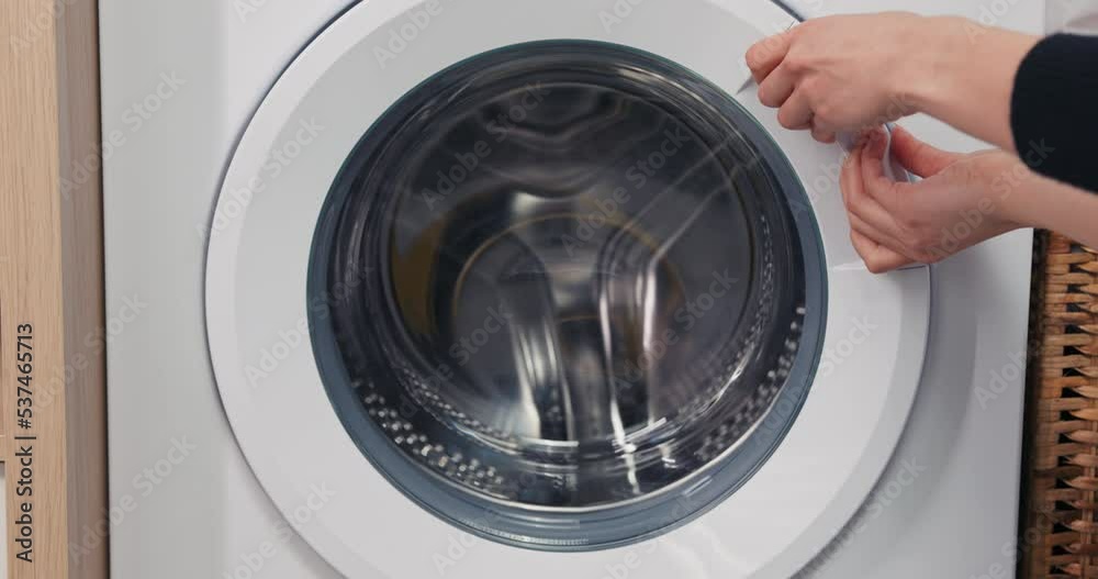 Close-up of hands trying to open the door of the washing machine, which is jammed broken. Anger, upset over a laundry problem. Close-up of hands trying to open the door of the washing machine, which is jammed broken. Anger, upset over a laundry problem.