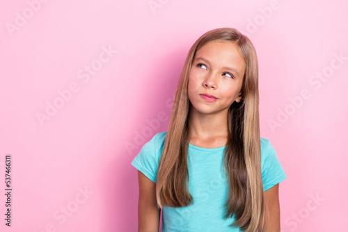 Photo of little minded smart preteen girl wear blue t-shirt looking pouted lips ponder idea plan how go home from school earlier isolated on pink color background