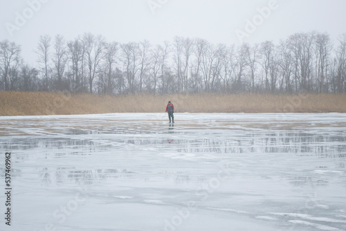 Lonely fisherman on the lake in winter mist