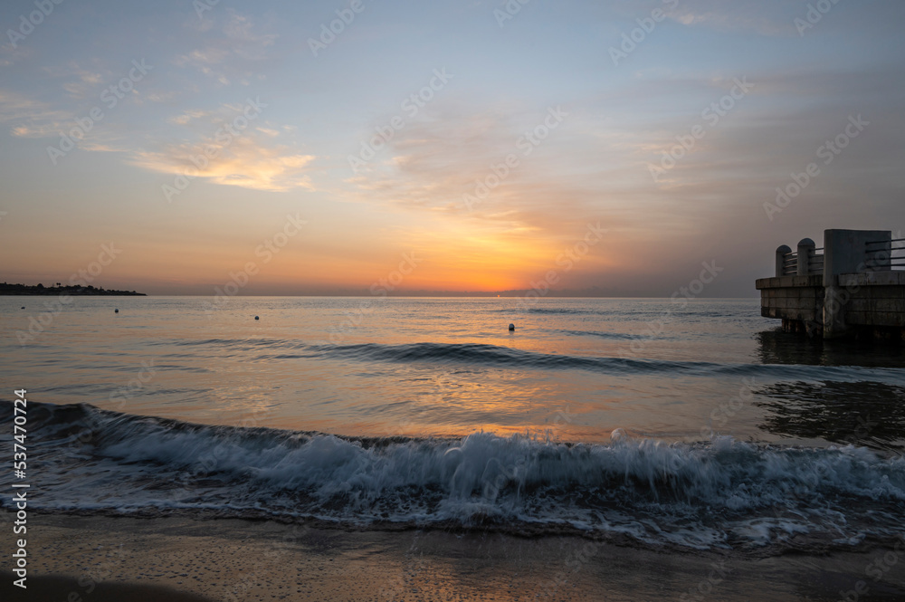 A splendid sunrise with its beautiful colors on the sea seen from the beach of Avola near the roundabout on the sea