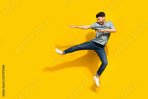 Full length profile side photo of positive man coach training exercises fighting look empty space isolated on yellow color background photo