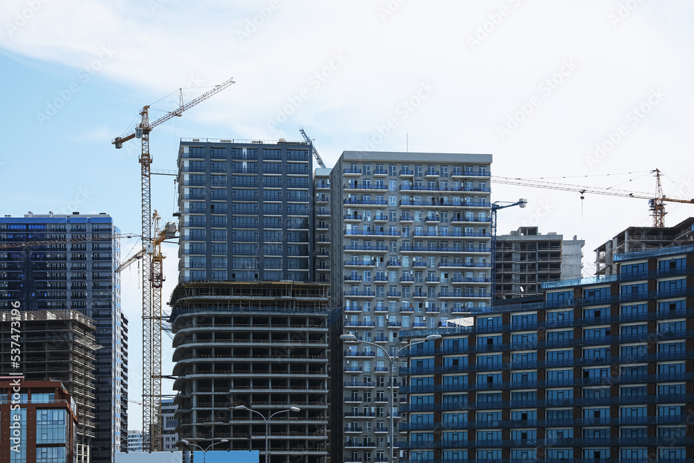 Construction site with tower cranes near unfinished buildings