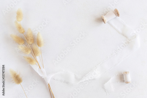 Hare's tail grass and silk ribbons on white top view, copy space. Romantic scene photo