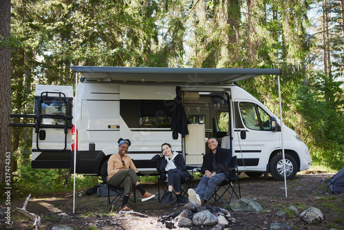 Friends relaxing in front of camper van photo