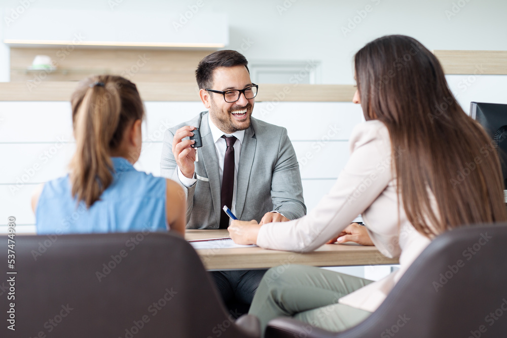© zorandim75 - Happy family choosing a new car in a showroom. Customer buying a car at dealership.