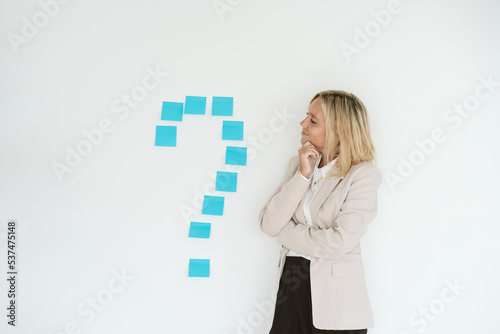 Businesswoman looking at question mark on the wall