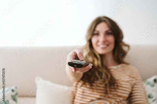 Young woman using remote control on sofa at home