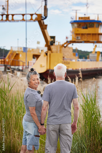 Senior couple holding hands and looking at industrial barge photo