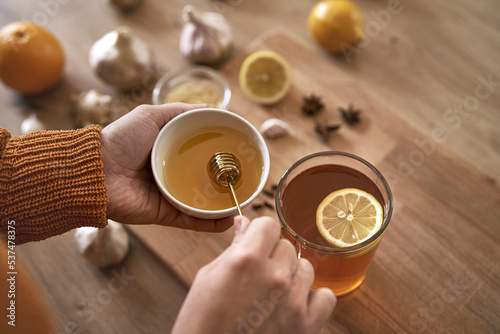 Close up of woman's hand with honey adding to tea photo