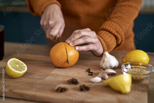 Close up of caucasian woman cutting orange for immunity in the kitchen