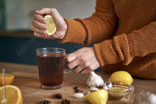 Фотография Close up of woman's hand squeezing lemon for tea