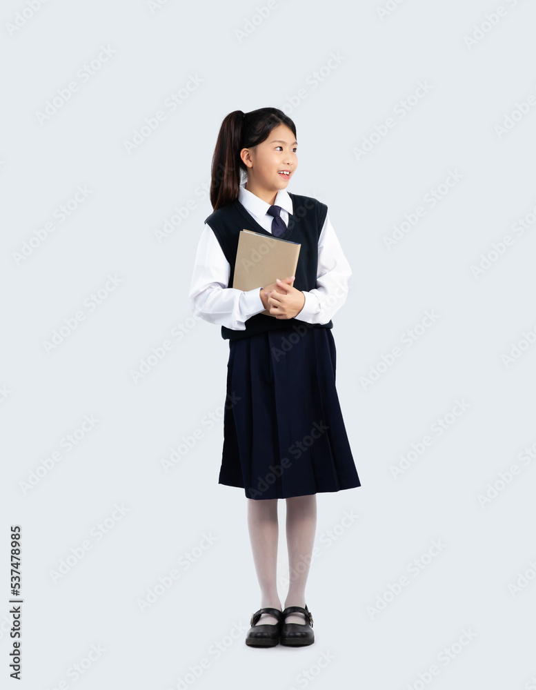 Elementary school kid in student uniform holding book standing on white background. Back to shcool concept. Elementary school kid in student uniform holding book standing on white background. Back to shcool concept.