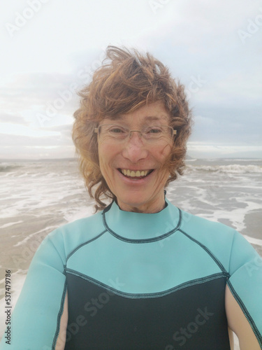 Mature woman takes a selfie before cold water swimming. Open, wild or cold water swimming in the sea is known to have benefits for physical and mental health. The weather is rough.