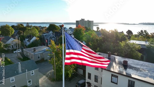 Portland Maine. Aerial establishing shot of Munjoy Hill neighborhood. Casco Bay and Atlantic Ocean sunlight reflection. American flag. photo