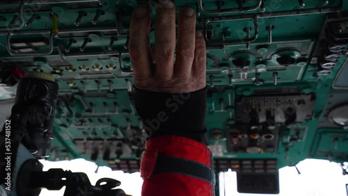 Inside helicopter cabin. Fingers switch toggle switches on top panel of helicopter. Preparing for takeoff