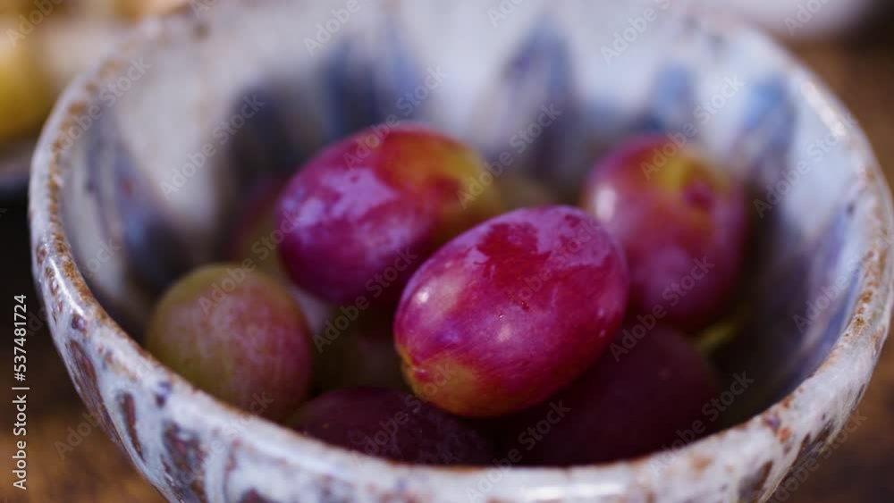 Small bowl with red grapes being placed down, close-up shot Small bowl with red grapes being placed down, close-up shot
