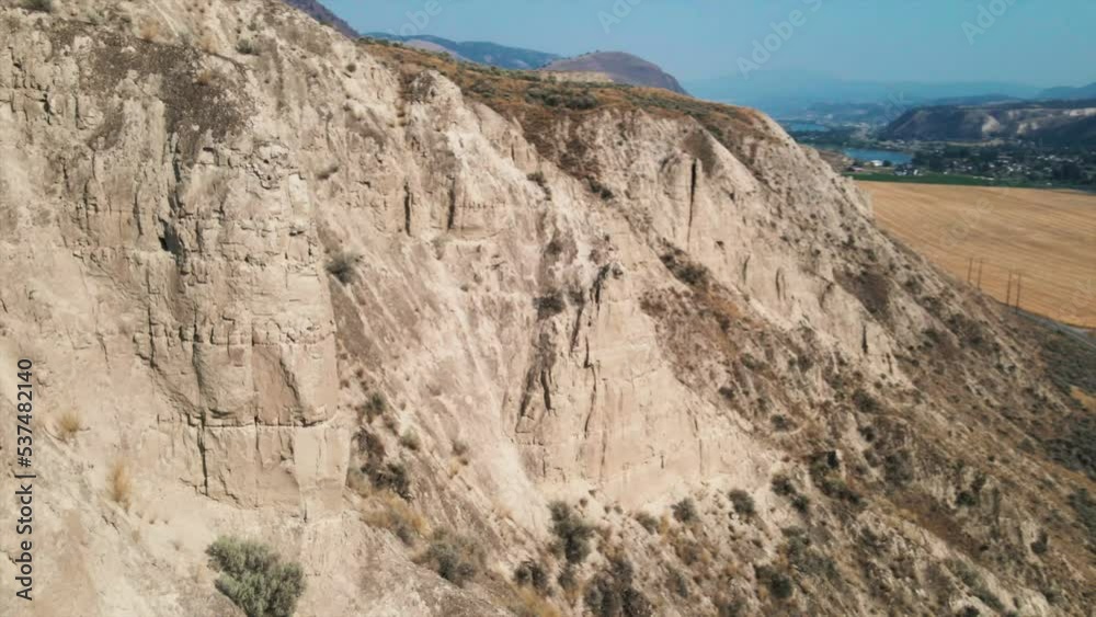 Aerial view of beautiful mountain with field and road as background. Peaceful drone footage of astonishing mountainous landscape under blue sky. Rocky formations Aerial view of beautiful mountain with field and road as background. Peaceful drone footage of astonishing mountainous landscape under blue sky. Rocky formations