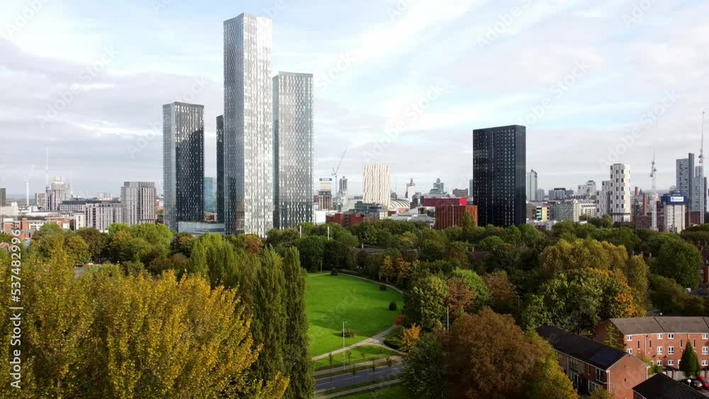 Manchester city parkland aerial view orbiting above trees to view modern high rise skyline Manchester city parkland aerial view orbiting above trees to view modern high rise skyline
