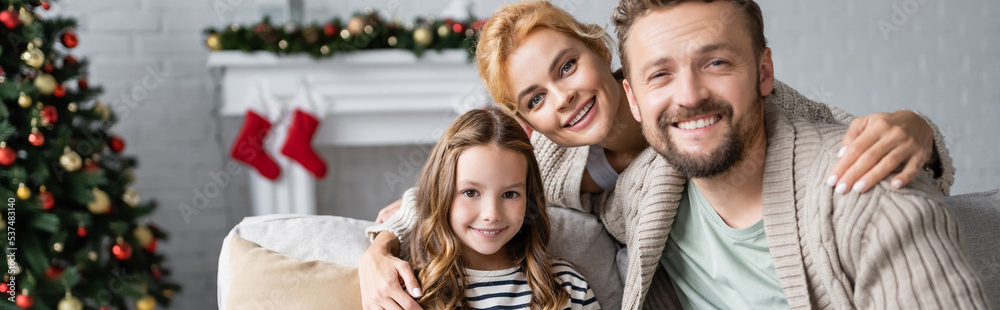Happy woman hugging daughter and husband during christmas at home, banner Happy woman hugging daughter and husband during christmas at home, banner