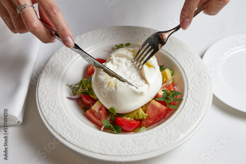 female hands with cutlery over mozzarella salad