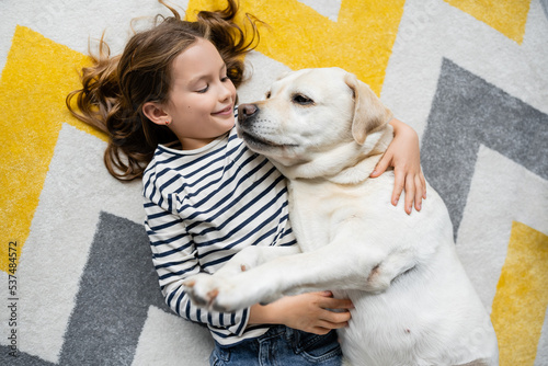 Top view of cheerful kid hugging labrador on floor at home © LIGHTFIELD STUDIOS
