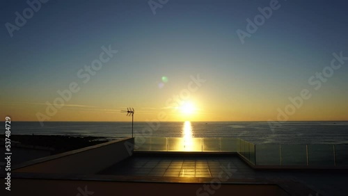 Time Lapse all'alba del sole che sorge dal mare tra le nuvole, vista da una terrazza fronte mare photo