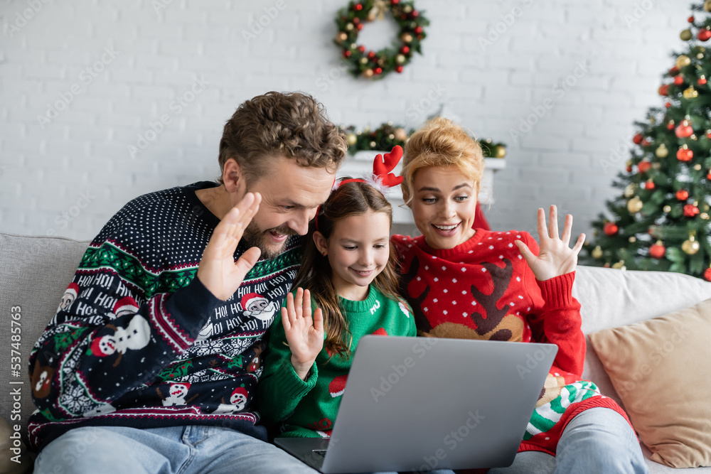 Cheerful family with kid having video call on laptop during new year at home Cheerful family with kid having video call on laptop during new year at home