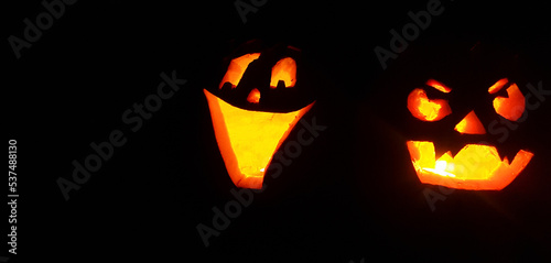 Carved Halloween pumpkin face with candle inside glowing in the darkness photo