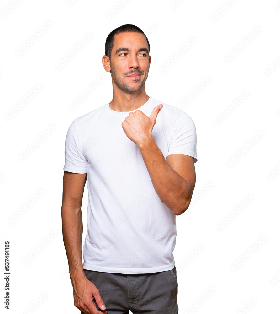 Happy young man pointing with his thumb
