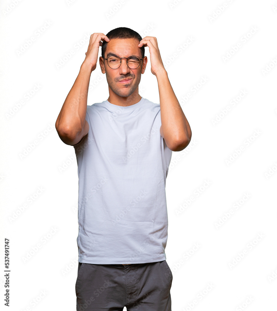 Concerned young man making a scratching gesture Concerned young man making a scratching gesture