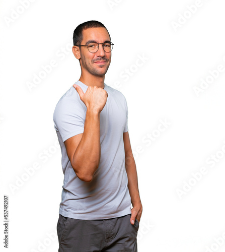 Happy young man pointing with his thumb